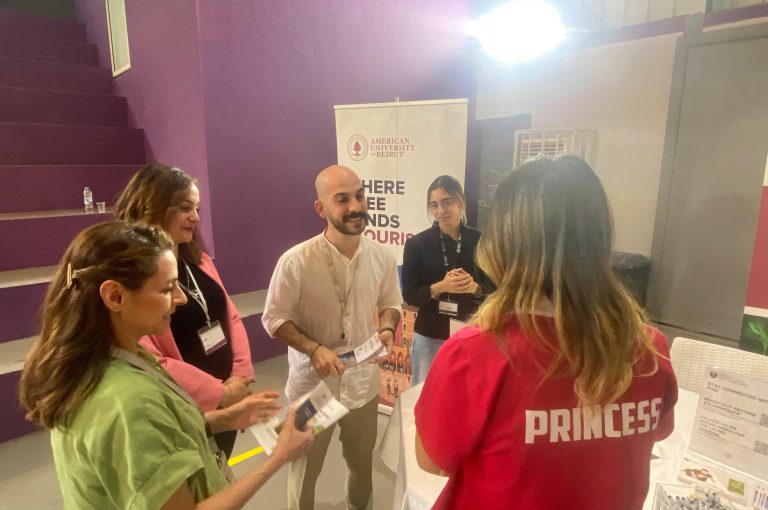 High school students in Grades 10–-12 visiting a university fair, exploring booths and talking to representatives.