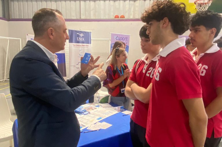 High school students in Grades 10–-12 visiting a university fair, exploring booths and talking to representatives.