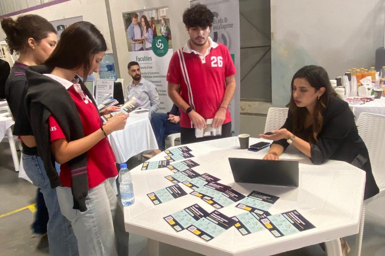 High school students in Grades 10–-12 visiting a university fair, exploring booths and talking to representatives.