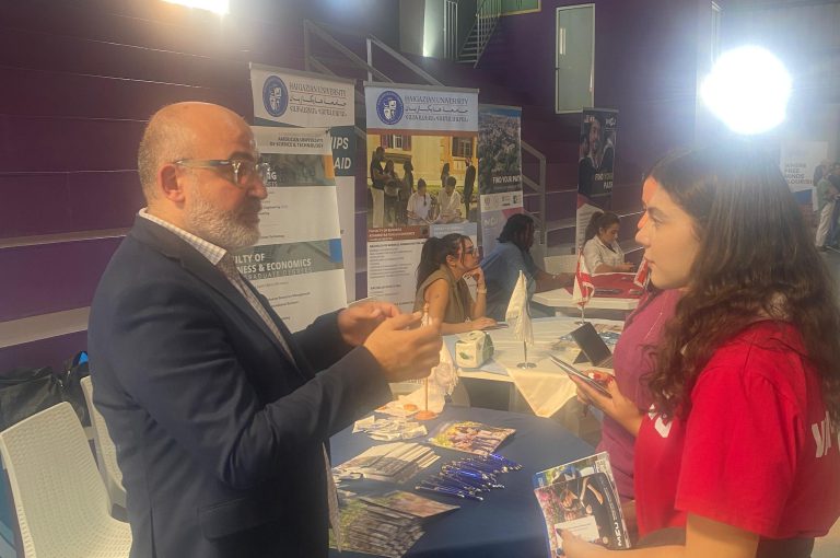 High school students in Grades 10–-12 visiting a university fair, exploring booths and talking to representatives.