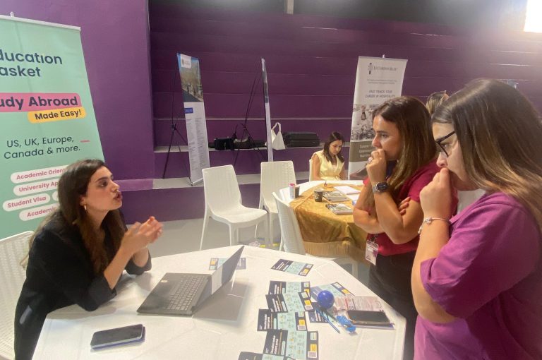 High school students in Grades 10–-12 visiting a university fair, exploring booths and talking to representatives.