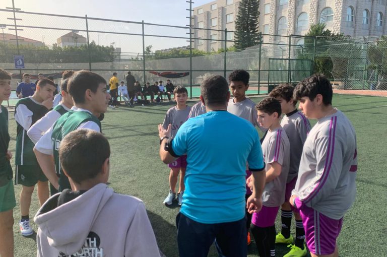 LWIS-AiS students playing football against St Jean Okaibe at the Lebanese Schools Tournament at NDU Zouk Mosbeh, showing teamwork and determination."