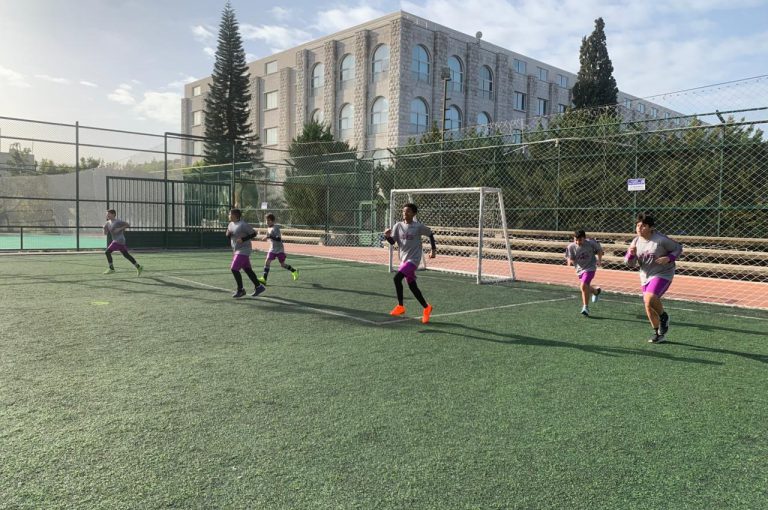 LWIS-AiS students playing football against St Jean Okaibe at the Lebanese Schools Tournament at NDU Zouk Mosbeh, showing teamwork and determination."