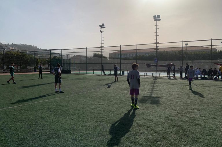LWIS-AiS students playing football against St Jean Okaibe at the Lebanese Schools Tournament at NDU Zouk Mosbeh, showing teamwork and determination."