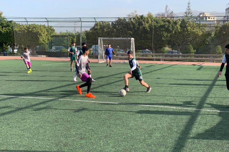 LWIS-AiS students playing football against St Jean Okaibe at the Lebanese Schools Tournament at NDU Zouk Mosbeh, showing teamwork and determination."