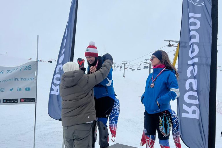 Leona on the podium after winning second place in the junior category at the Lebanese Alpine Ski Championship, wearing ski gear and holding her medal.