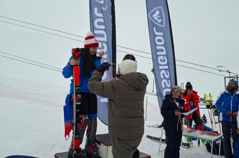 Leona on the podium after winning second place in the junior category at the Lebanese Alpine Ski Championship, wearing ski gear and holding her medal.