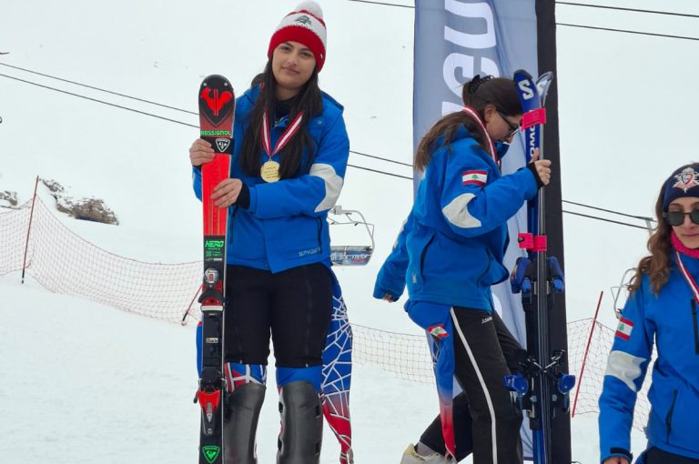 Leona on the podium after winning second place in the junior category at the Lebanese Alpine Ski Championship, wearing ski gear and holding her medal.