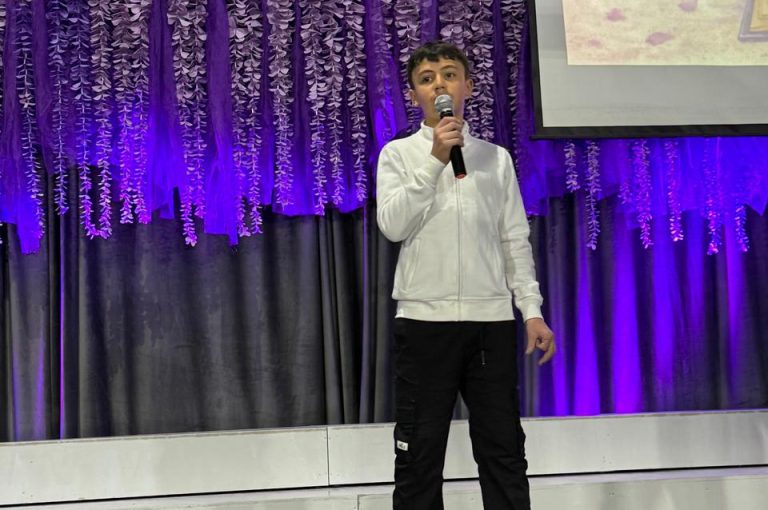 LWIS AIS students standing on stage, reciting poetry during Poetry Night event.