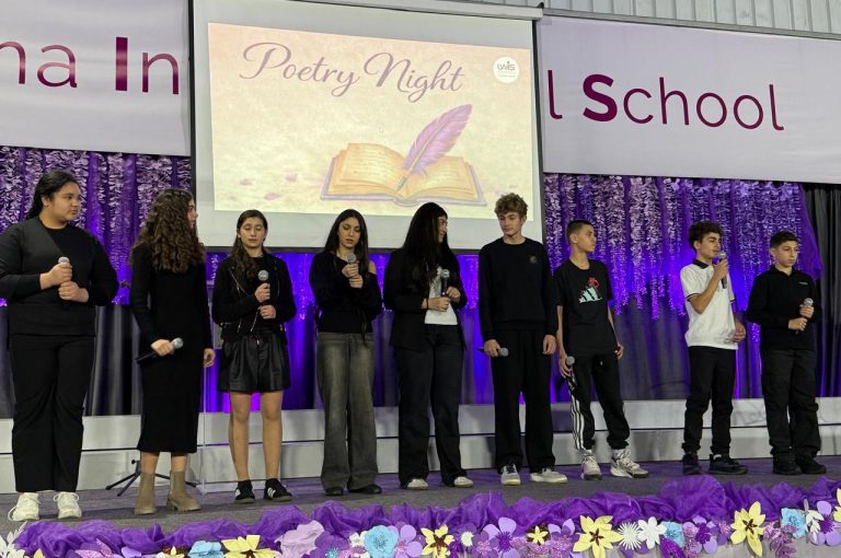 LWIS AIS students standing on stage, reciting poetry during Poetry Night event.