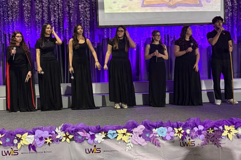 LWIS AIS students standing on stage, reciting poetry during Poetry Night event.