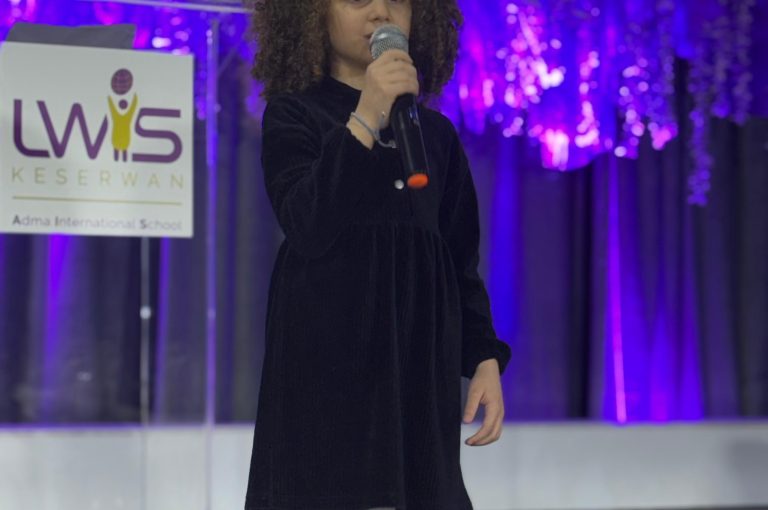 LWIS AIS students standing on stage, reciting poetry during Poetry Night event.
