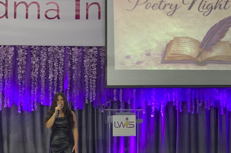LWIS AIS students standing on stage, reciting poetry during Poetry Night event.