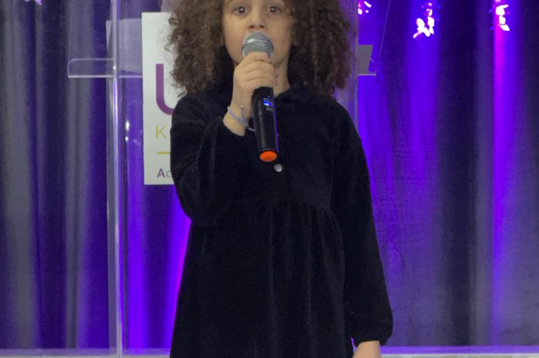 LWIS AIS students standing on stage, reciting poetry during Poetry Night event.