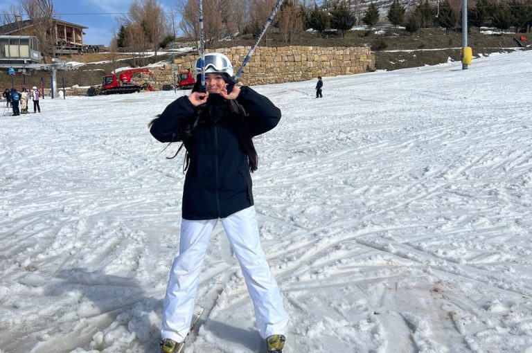 Students skiing and playing in the snow on a mountain during a school trip, with a bright winter landscape in the background.